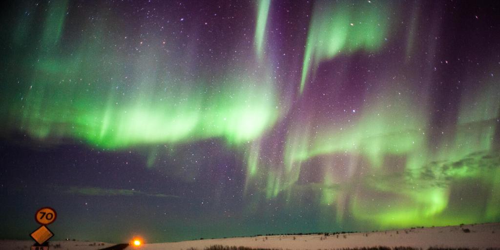 Northern lights across a starry sky, illuminating the snowy landscape in Husavik, Iceland 