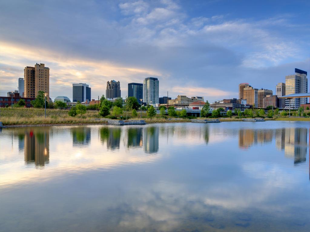 Birmingham, Alabama, USA with the city skyline of Birmingham from Railroad Park in the distance and the water reflecting the buildings in the foreground.