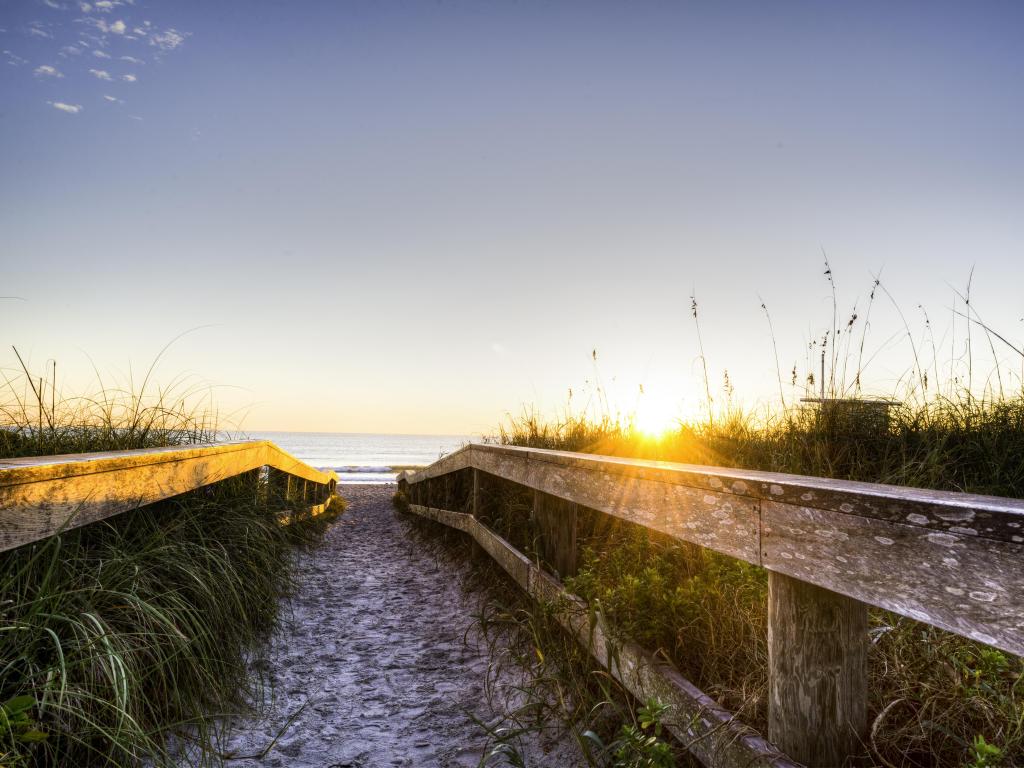 Cocoa Beach, Florida, USA taken at Sunrise with wooden fences leading towards the sea in the distance.