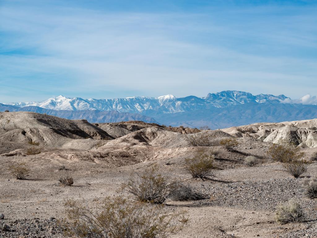 Tule Springs National Monument, Nevada with white gypsum hills in the foreground and a snow-capped mountain in the distance.
