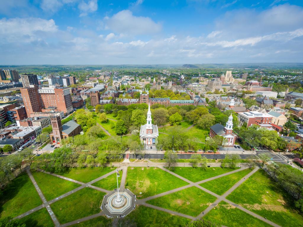 New Haven, Connecticut with a view of the New Haven Green in the foreground and the city in the background under a blue sky.