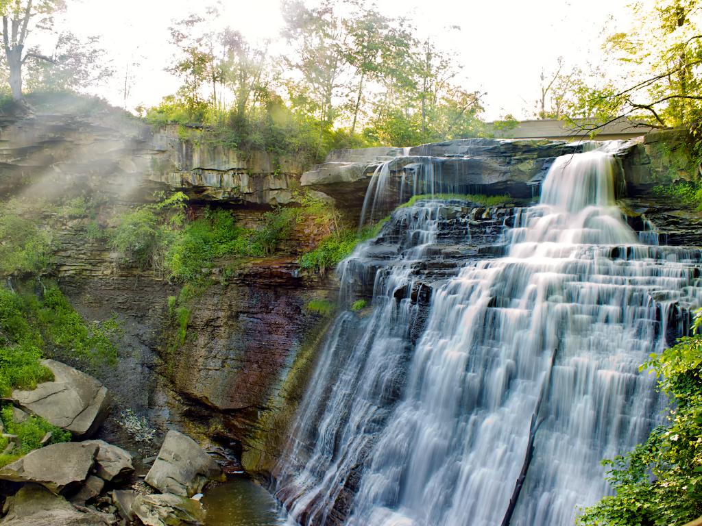 The flowing water with trees on the sides in Brandywine Falls at Cuyahoga Valley National Park in a bright day.