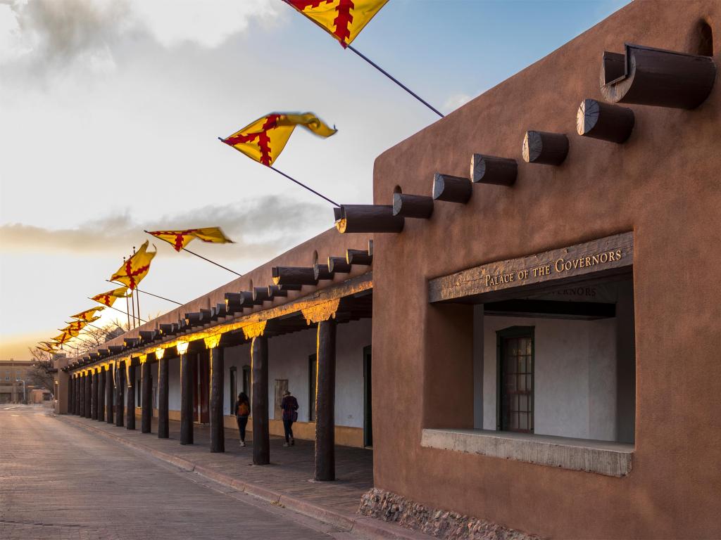 Flags flying above the Palace of the Governors, Santa Fe Plaza, State Capital of New Mexico at sunset on a spring evening