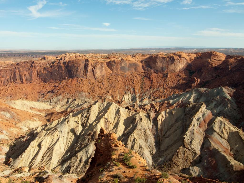 Panoramic view of Upheaval Dome Crater, Canyonlands National Park, with red and yellow jagged rock beneath a blue sky