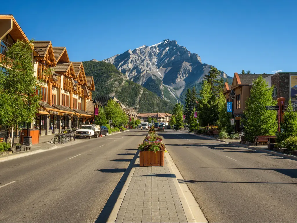 Banff, Canada with a scenic street view of the Banff Avenue on a sunny summer day and the imposing mountain in the distance. 