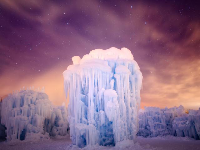 Towering ice "castle" formation during nighttime with stars visible in the sky