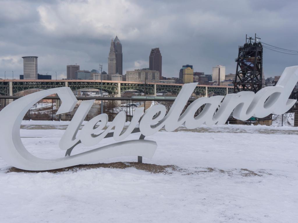 Close up shot of the Cleveland sign in the winter snow, with a view of downtown in the background