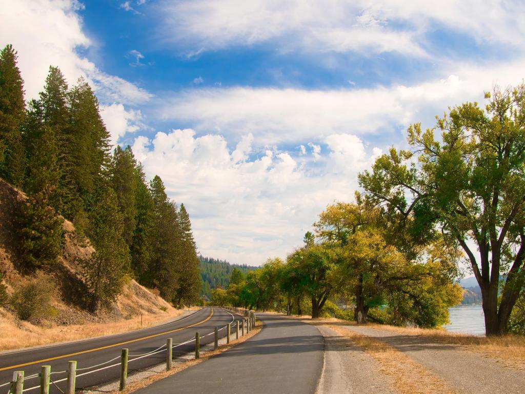 On a sunny Autumn day near Coeur D'Alene, ID, the North Idaho Centennial Trail passes between a road and the shores of Lake Coeur d'Alene.