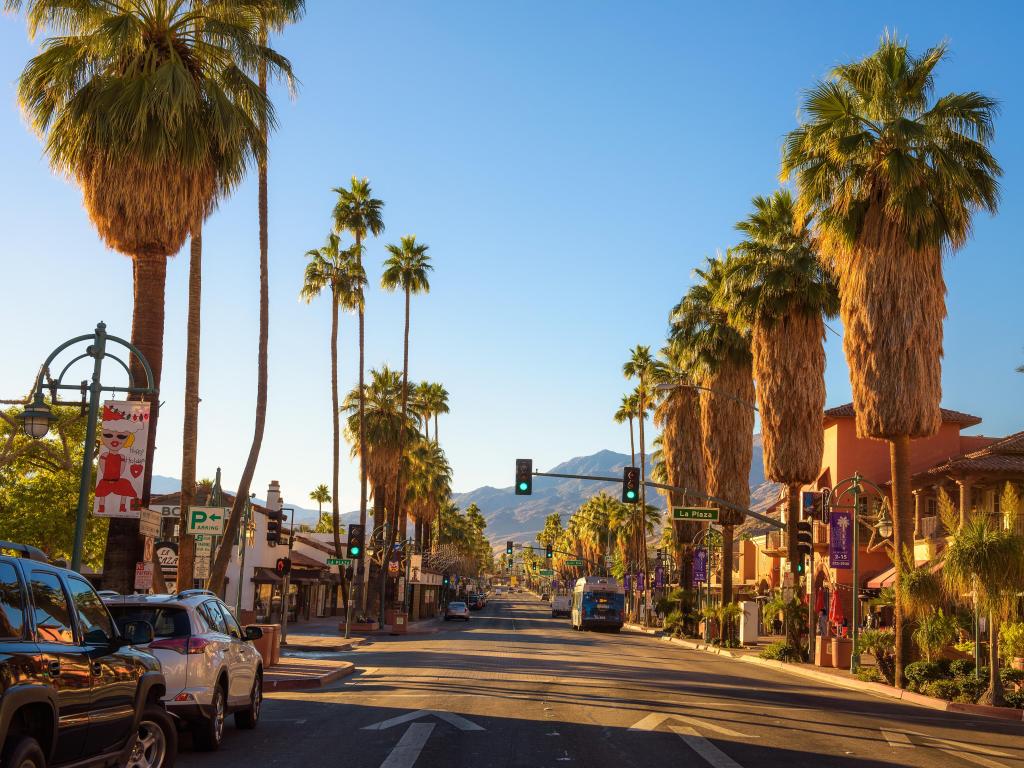 Palm Springs, California, USA with a street view at sunrise, palm trees lining the street.