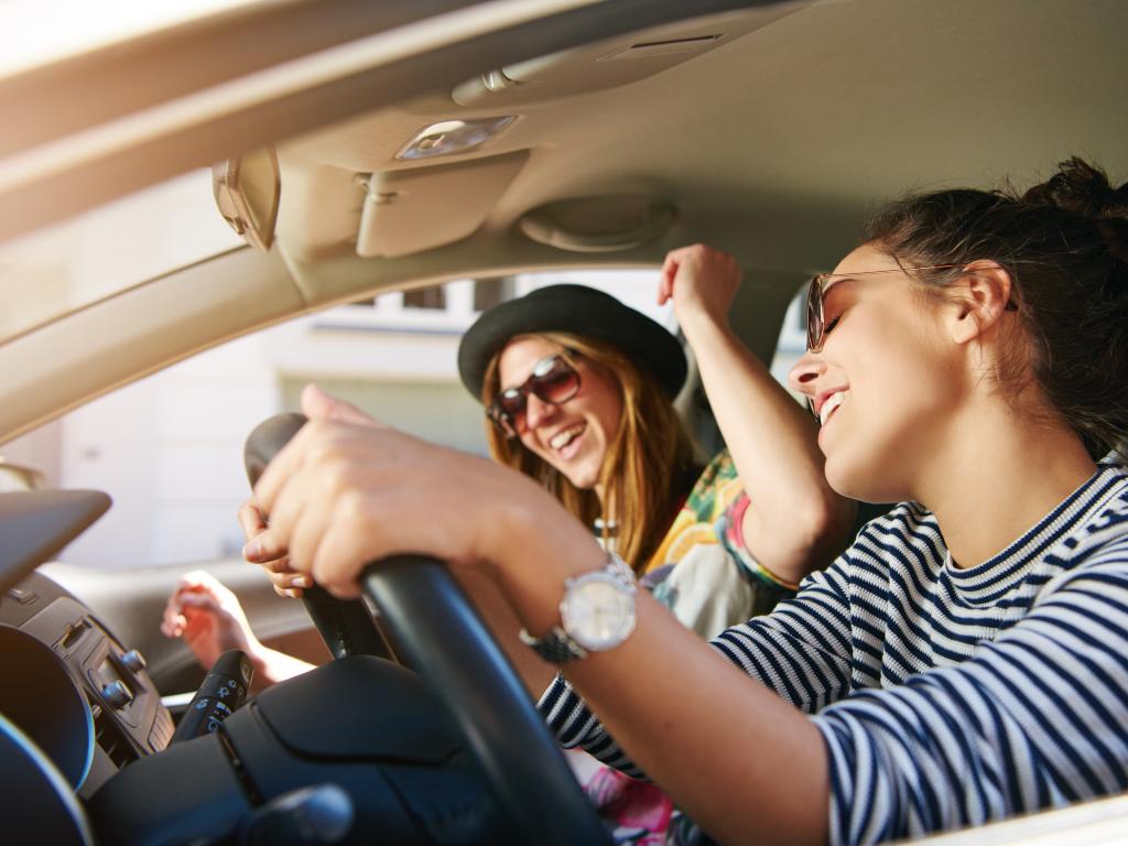 Two women enjoying playing Sing The Next Line game in their car.