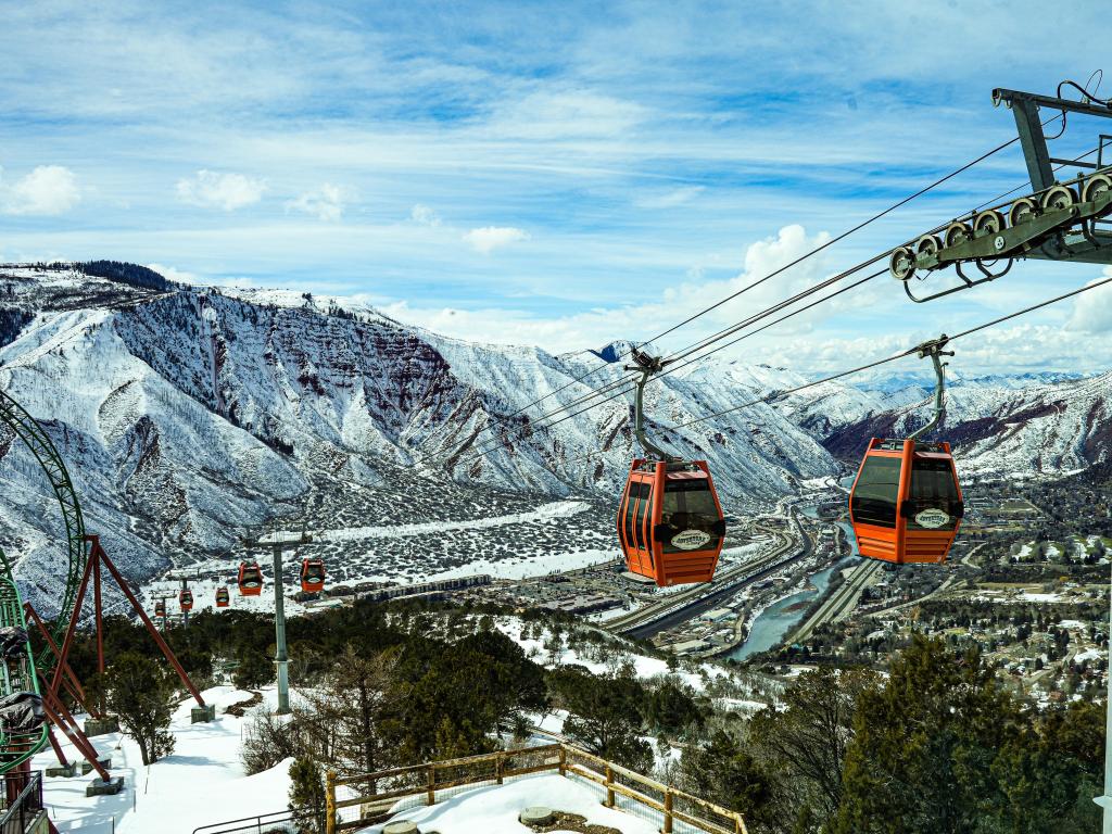 Gondolas over snow covered valley and mountains