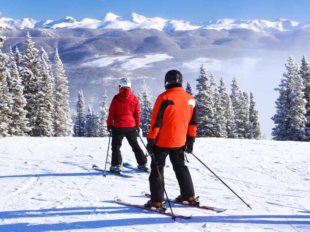 Skiing down the Rocky Mountains at Breckenridge Resort in Colorado winter snow wearing a colorful red ski jacket and helmet.