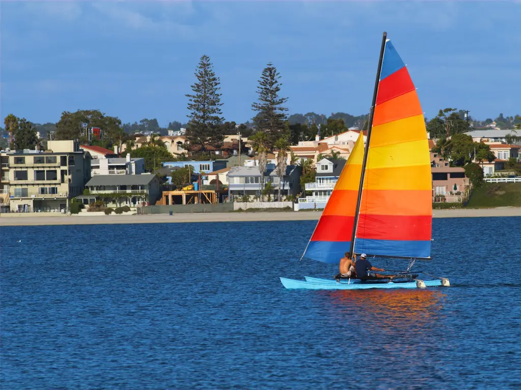 Two men are sailing a yacht with colorful sail in Mission Bay, San Diego, California.
