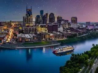 Evening aerial view of Nashville city, with bright lights across stadium and city buildings, against star filled skies