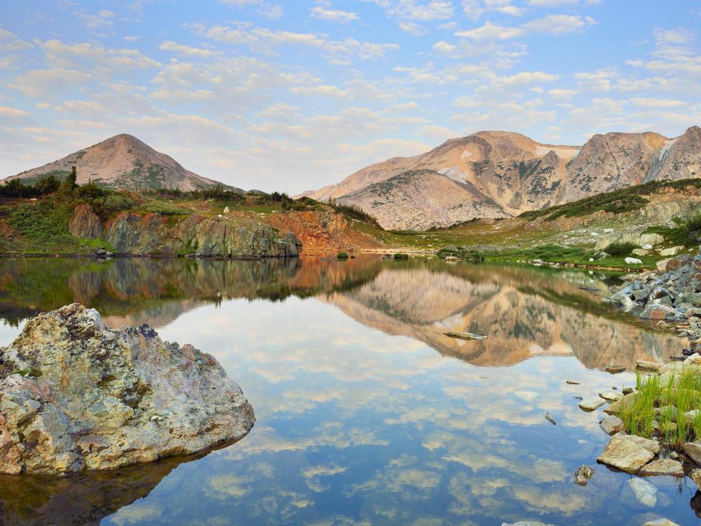 Medicine Bow Mountains, Wyoming, USA during summer with a rock and lake in the foreground and mountains in the distance. 