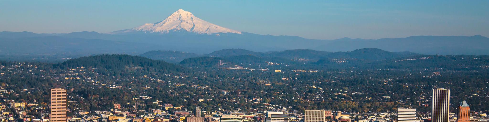 Cityscape of Portland, Oregon and Mount Hood towering in distance, autumn afternoon.