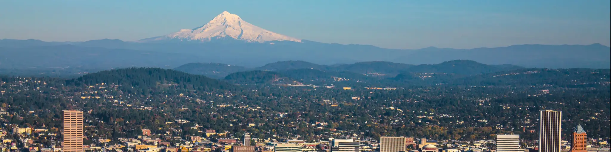 Cityscape of Portland, Oregon and Mount Hood towering in distance, autumn afternoon.