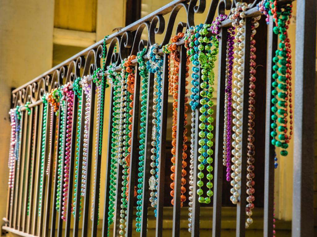 A close-up shot of a row of mardi gras beads hanging from a balcony in the French Quarter of New Orleans