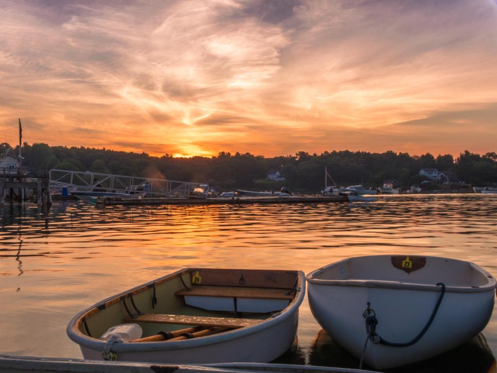 Early morning summer sunrise over calm water and john boats near a working lobster wharf in Muscongus Bay, Maine