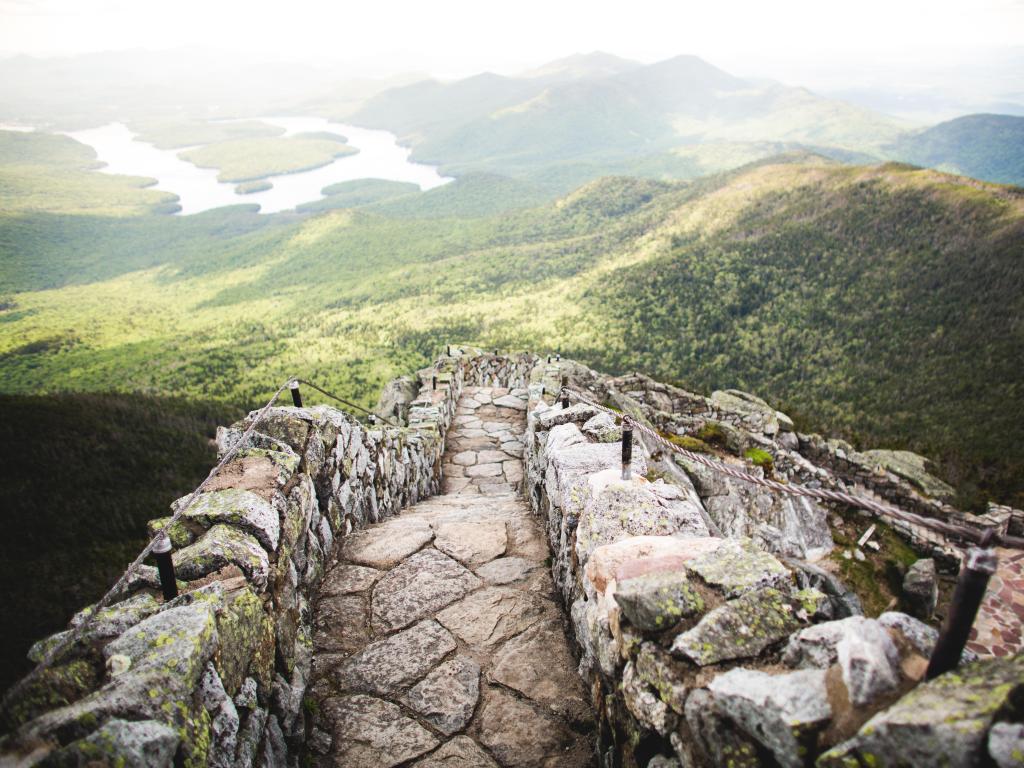 Whiteface Mountain, Adirondack Mountains, USA with a stone walkway on top of Whiteface Mountain with a scenic view of the green valleys below.