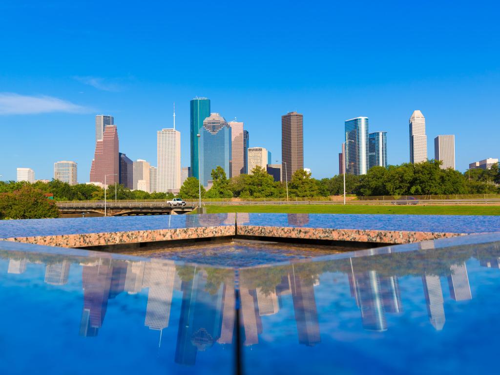 Reflection of high rise buildings in clear water of stone memorial sculpture