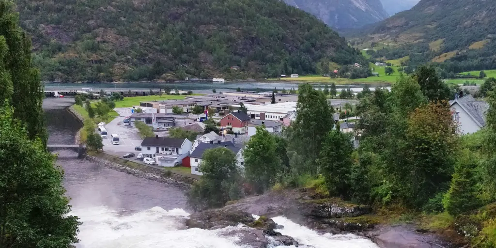A waterfall gushes down from a mountain through the village of Hellesylt in Norway