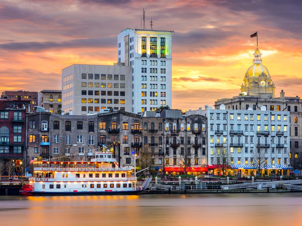 Savannah, Georgia, USA riverfront skyline taken at sunset with cruise boats on the river.