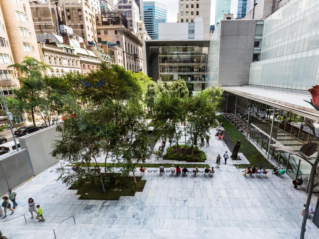 Inside courtyard and seating dotted with trees and surrounded by museum buildings, at Museum of Modern Art in New York