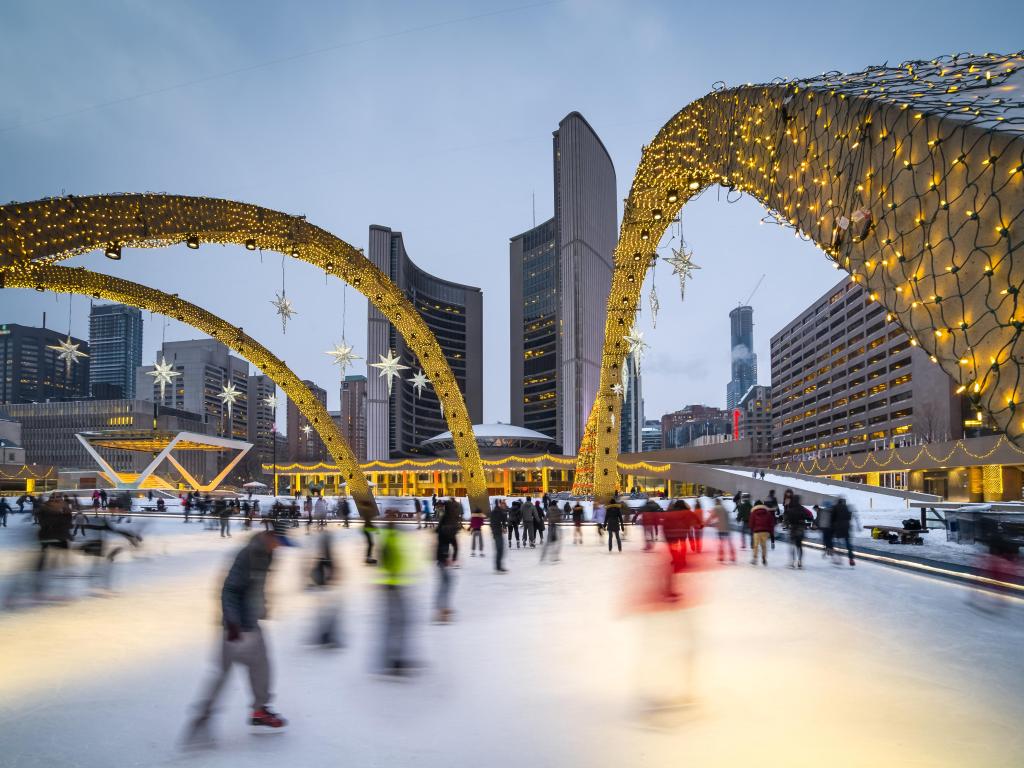 People iceskating at Nathan Phillips Square with Christmas decorations hanging above