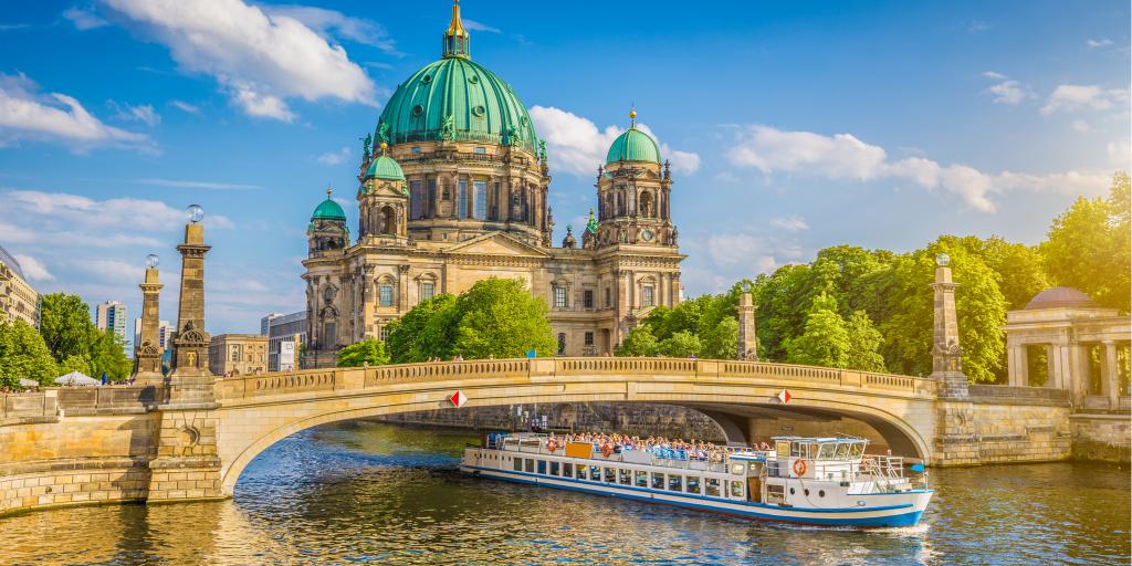 View of the Berlin Cathedral on Museumsinsel (Museum Island) with a boat going along the Spree river in Berlin