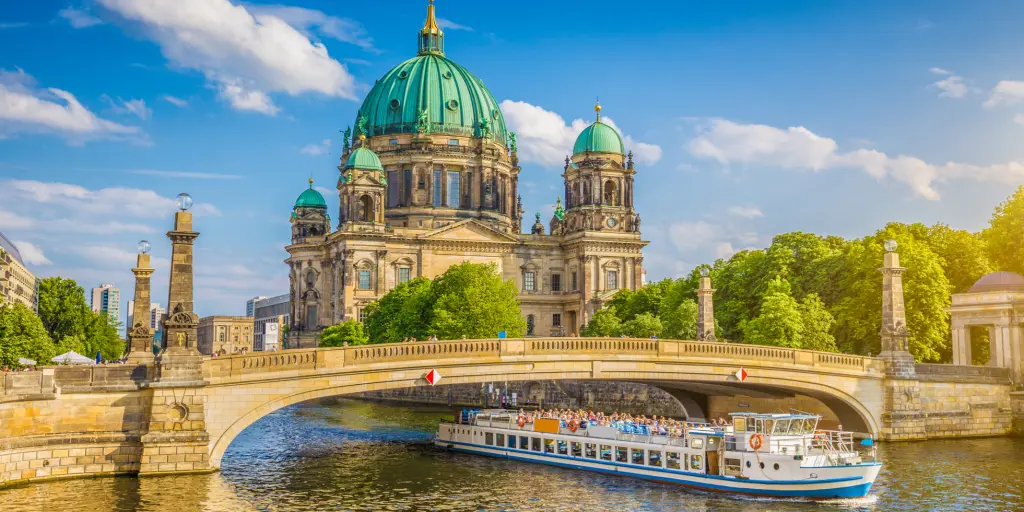 View of the Berlin Cathedral on Museumsinsel (Museum Island) with a boat going along the Spree river in Berlin