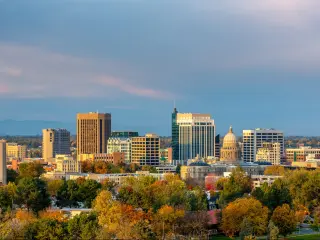 Boise, Idaho, USA with the city skyline taken during fall, trees in the foreground and a sky with pinks and blues.