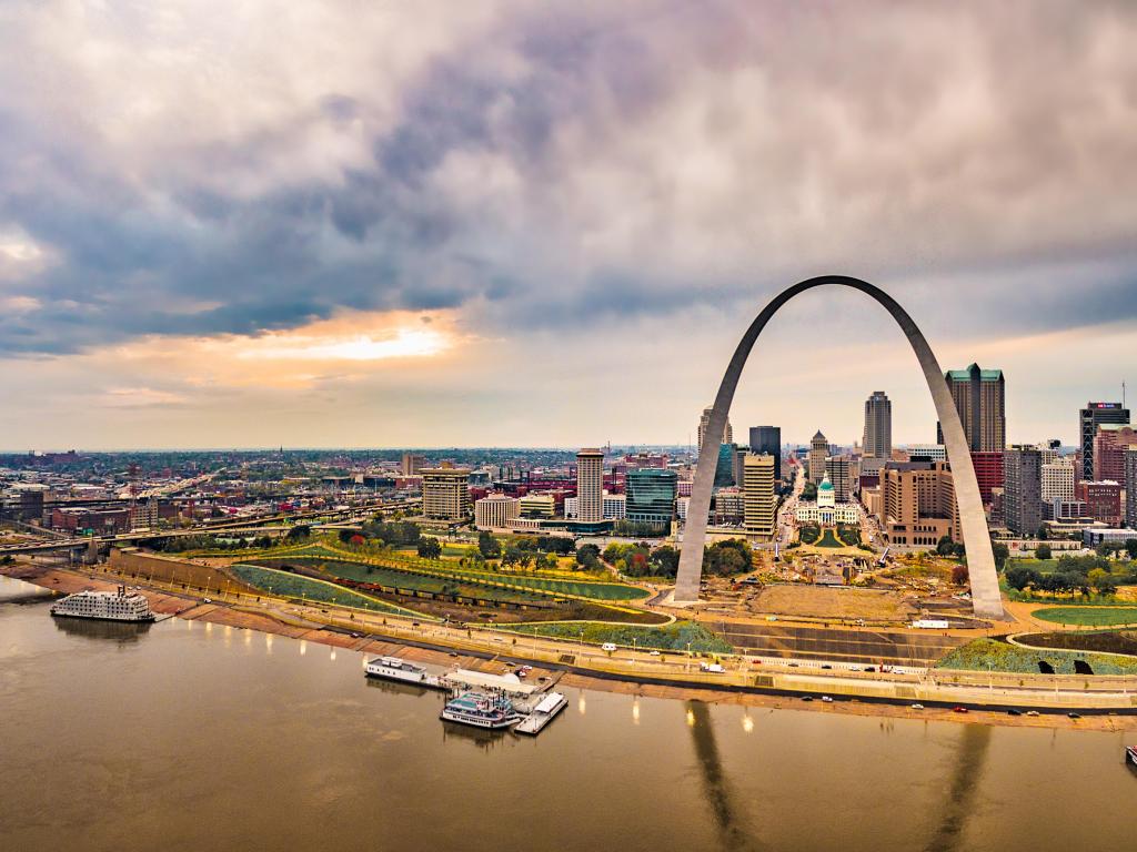 St. Louis, USA with the river in the foreground and the city and famous arch standing proud below a cloudy sky.