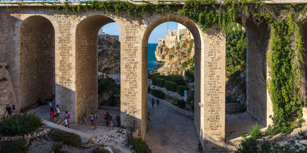 The archways of a bridge with the sea visible in the distance 