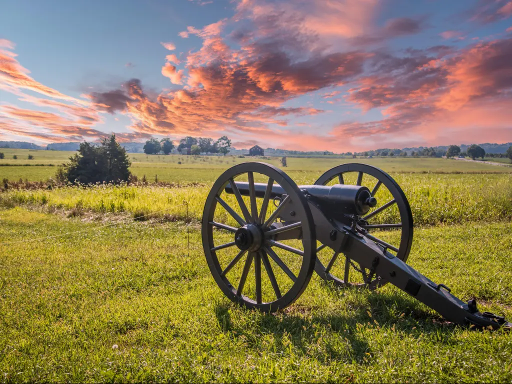 Gettysburg, USA with a canon aiming at a battlefield surrounded by grass and taken at sunset with a beautiful sky above.