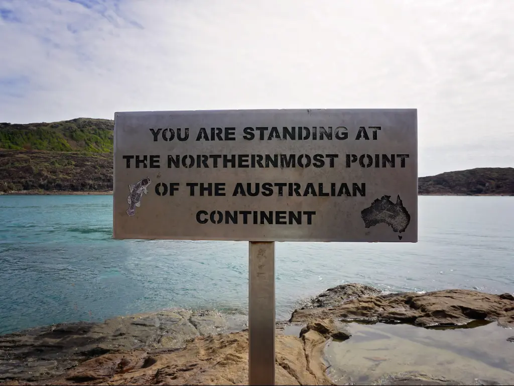 Sign at Cape York, Australia's northernmost point, with the beach in the background