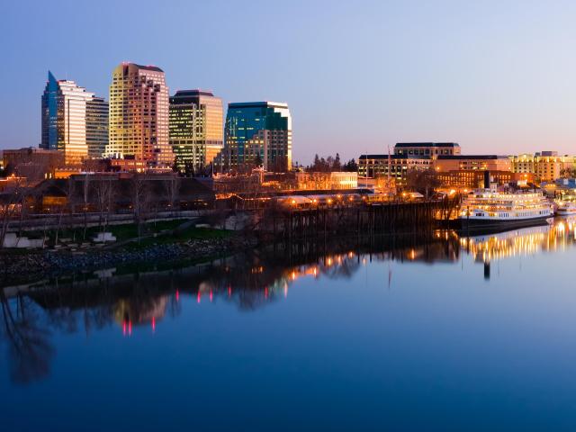 Sacramento Skyline at night with water and boats in the foreground and skyscrapers behind