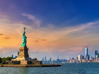 Panoramic view of Manhattan in the distance with the Statue of Liberty in view during sunset
