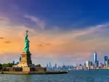 Panoramic view of Manhattan in the distance with the Statue of Liberty in view during sunset