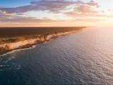 Nullarbor, South Australia taken as an aerial shot of Bunda Cliffs in the distance and the sea in the foreground as the sun is setting.