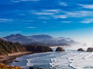 White foam waves lapping along Cannon Beach shoreline with Haystack Rock in the background