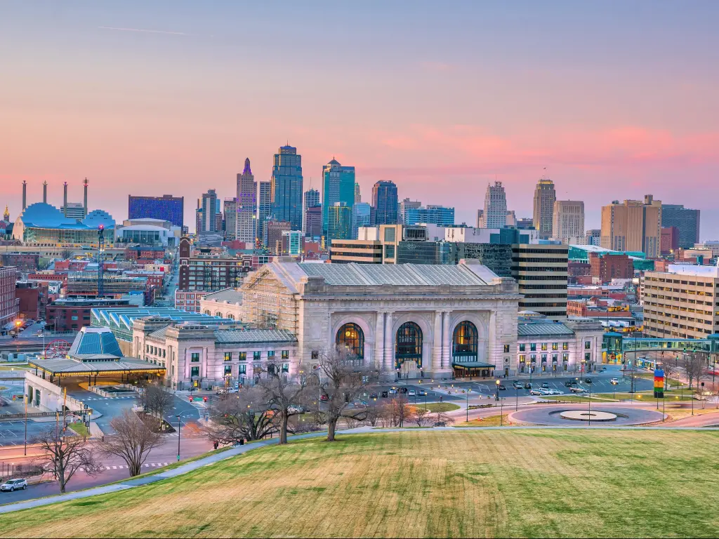 Kansas City, Missouri, USA downtown skyline with Union Station taken at sunset with a grassy verge in the foreground.