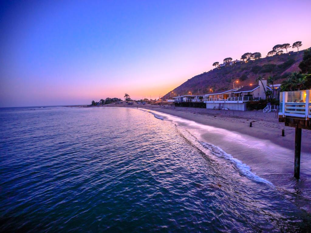 Malibu, California, United States with a scenic coastal landscape with Santa Monica Mountains and Surfrider Beach at dusk. 