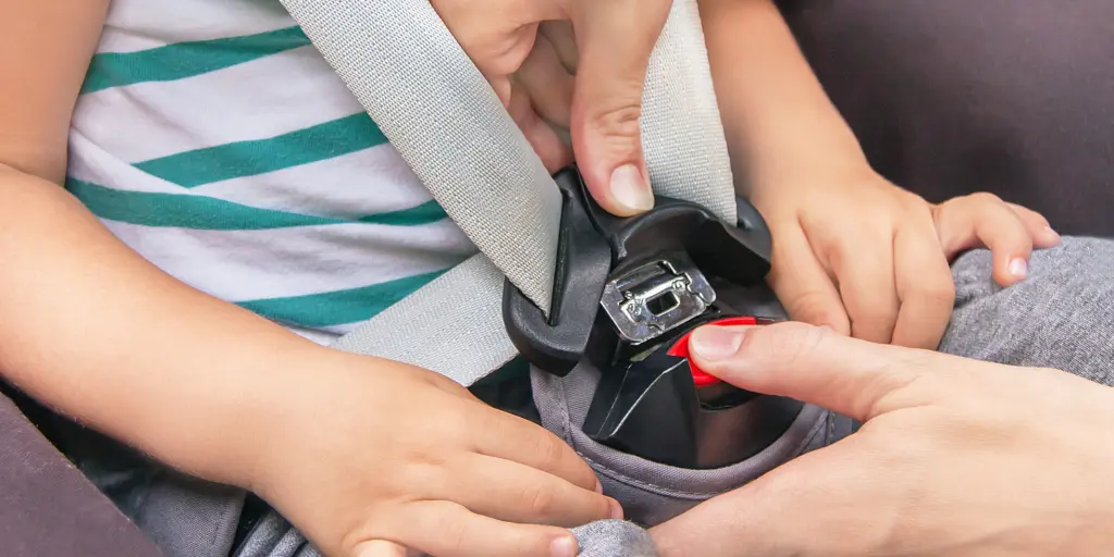 A parent fastening child's seatbelt