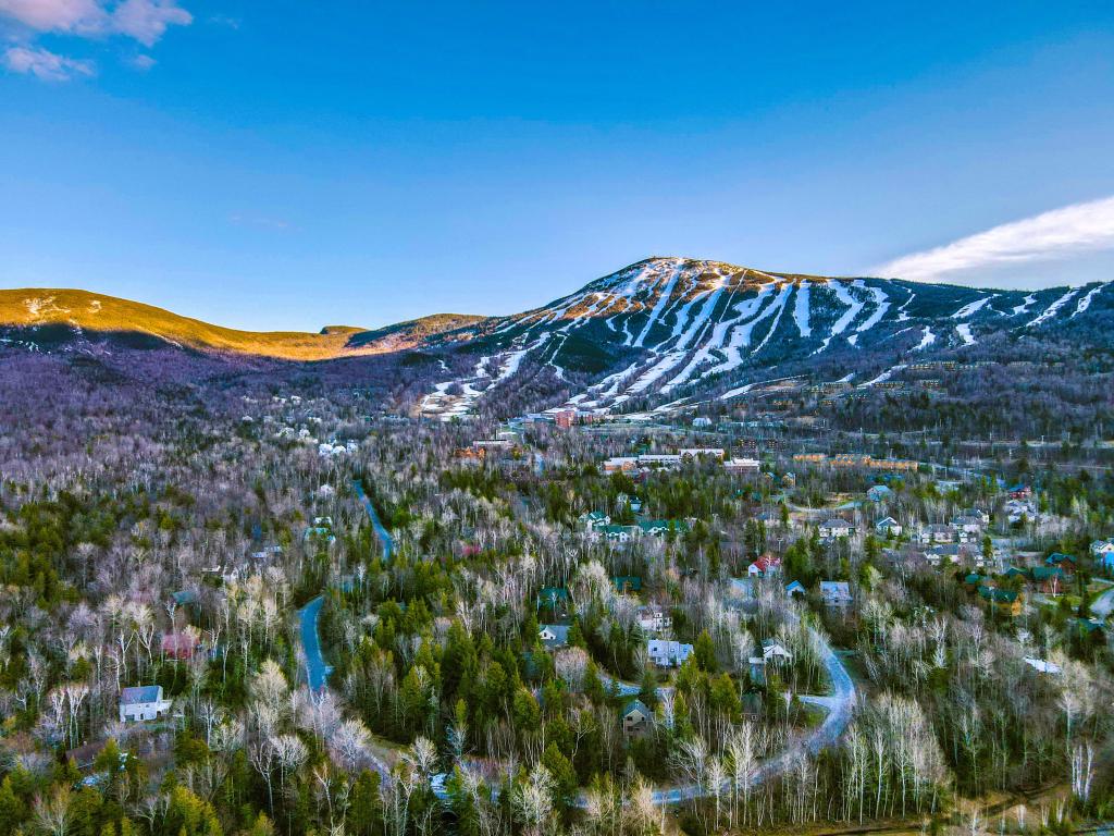 Sugarloaf Mountain Carrabassett Valley, ME, USA taken on a sunny day with the mountain covered in snow and the valley and trees in the foreground.