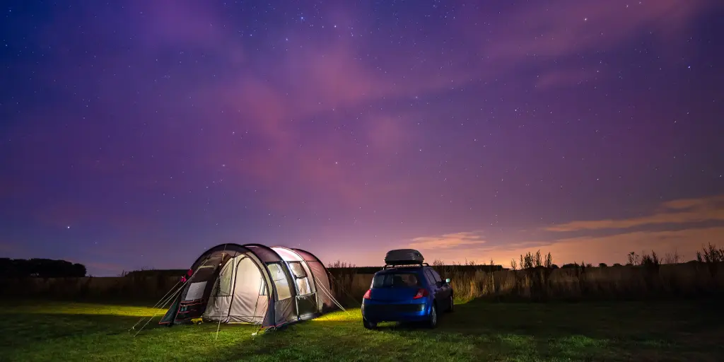 Tent and car under the night sky on a road trip