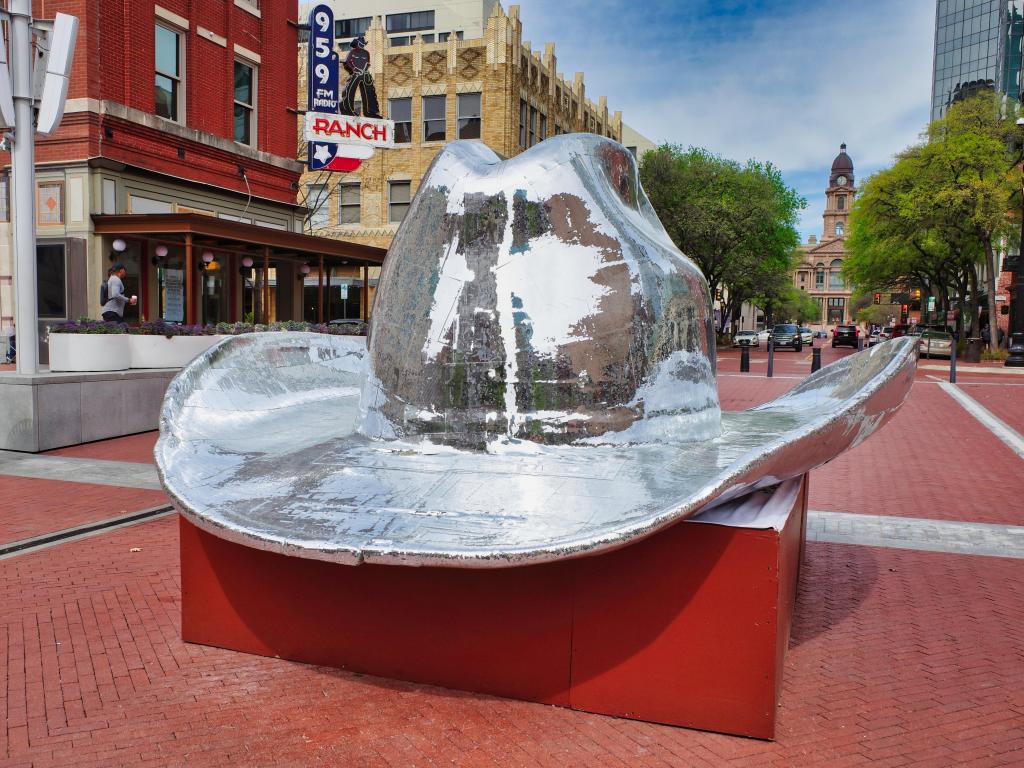 A metal cowboy hat statue sitting on a red pedestal in Sundance Square in Fort Worth.