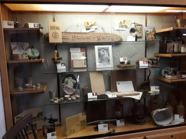 Mining memorabilia and artifacts in a glass display case, including photos, newspaper clippings and small gadgets