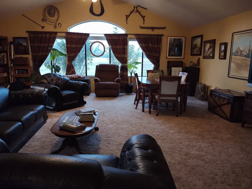 Cozy interior view of the shared lounge at the B&B with several chairs and sofas, as well as a small dining table