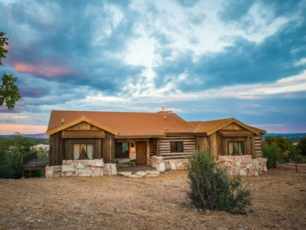 Outdoor view of wooden lodge and surrounding landscape at sunset, at Zion Mountain Ranch 